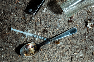 A used spoon and syringe lying on the ground