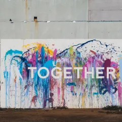concrete wall with splashes of different colours with word together 