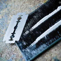 lines of cocaine on a mirror alongside a razor blade