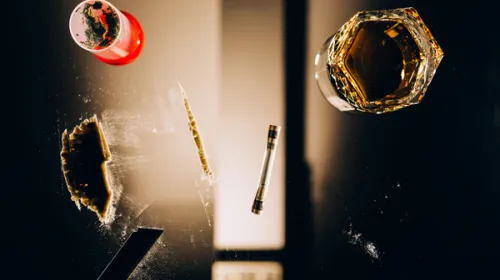 View through a glass table with a glass of alcohol, powder and a syringe