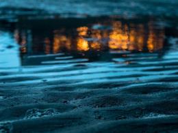 A puddle of water with light reflections on wet sand