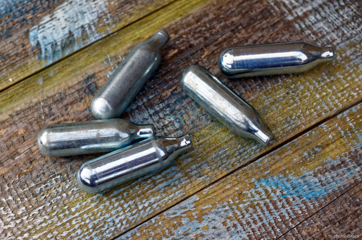Disposed silver laughing gas cartridges on a wooden table