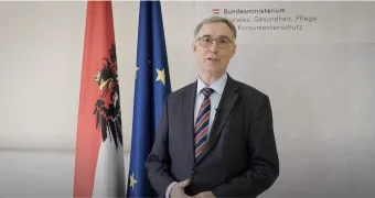 screen shot of Franz Pietsch before a European and Austrian flag making a speech